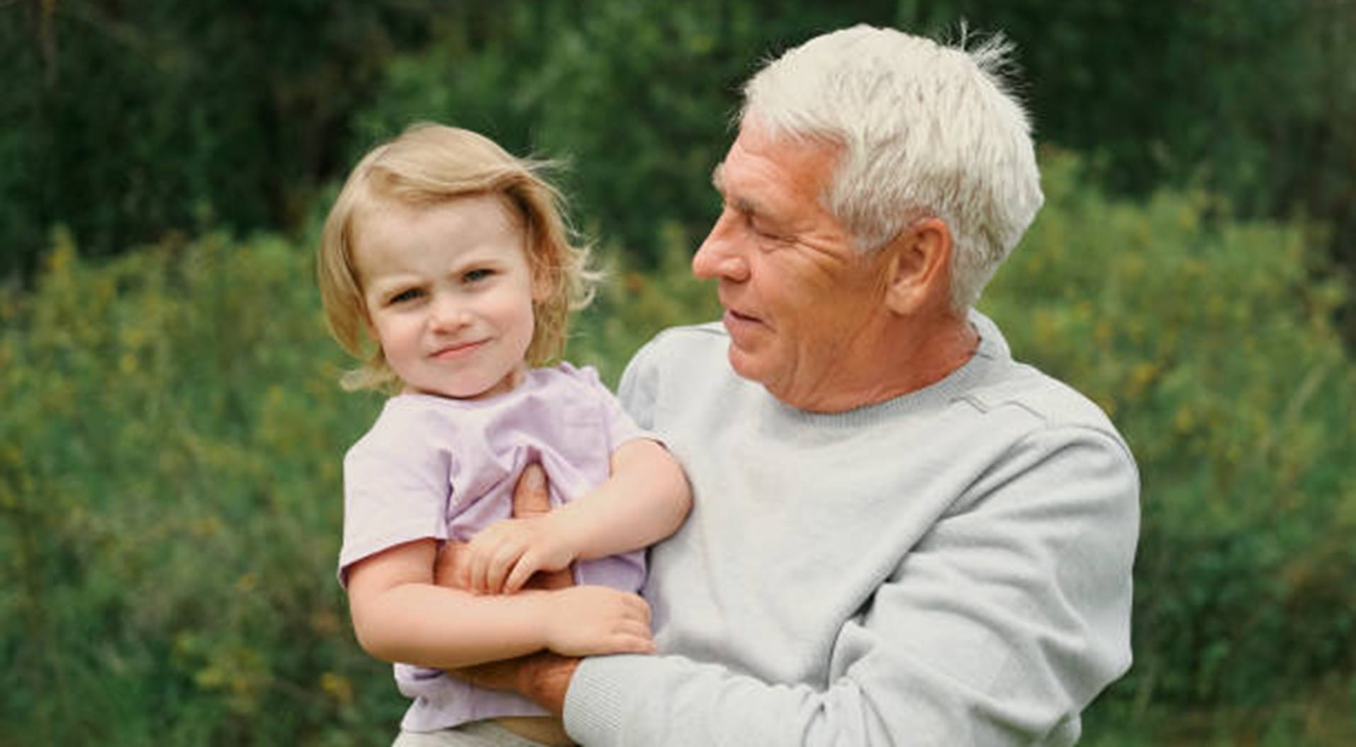 Grandfather and grandchild baby have fun during walk In Park. Happy family. Old man grandpa hugging 2 years child girl at summer day. Smiling Senior male spending time with his granddaughter together stock photo